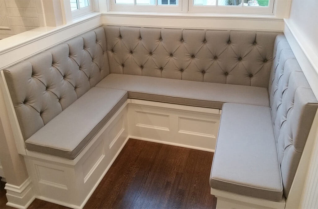 A kitchen bench with tufted cushions and wooden floors